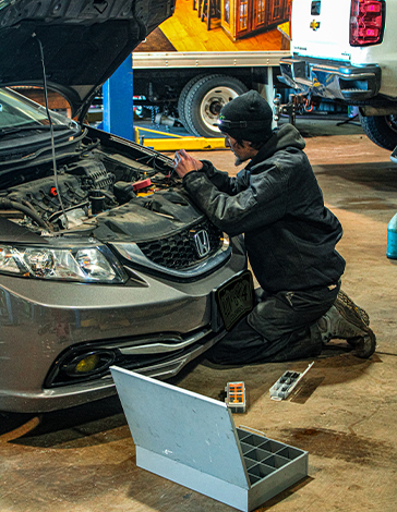 Fry's technician working under the hood of a Honda sedan in the shop bay